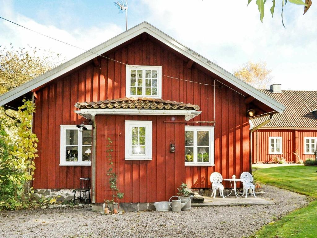 un granero rojo con dos sillas delante en 8 person holiday home in Varg n, en Västra Tunhem