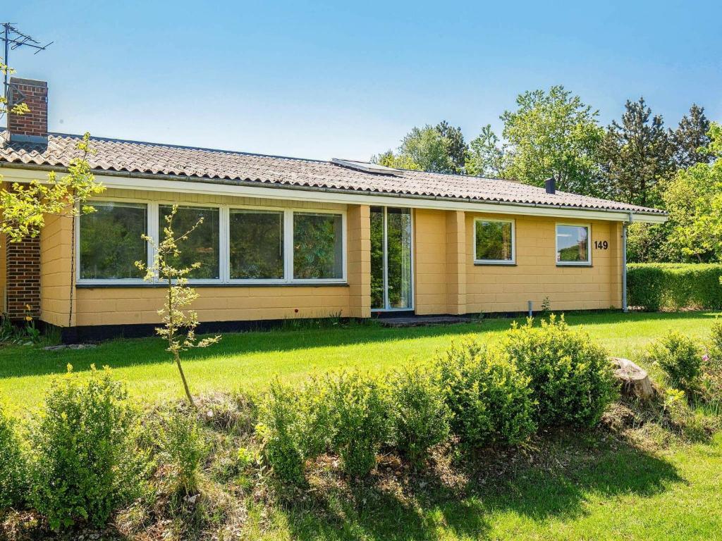 a small yellow house with a green yard at 6 person holiday home in Fars in Farsø