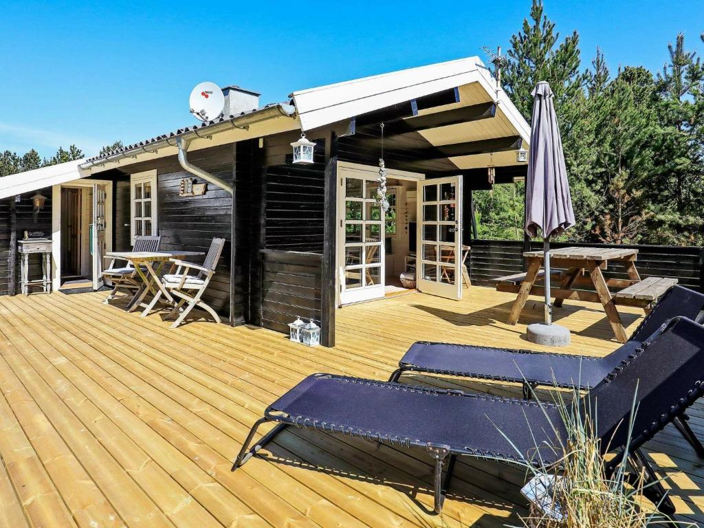 a wooden deck with a picnic table and an umbrella at 6 person holiday home in Jerup in Jerup