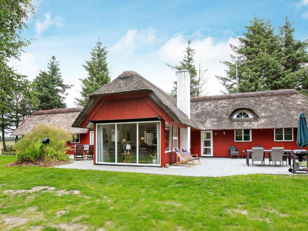 Cette maison rouge dispose d'un toit de chaume et d'une terrasse. dans l'établissement 8 person holiday home in Bl vand, à Blåvand