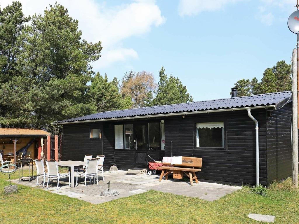 a black cabin with a patio and a table and chairs at 5 person holiday home in Vejers Strand in Vejers Strand