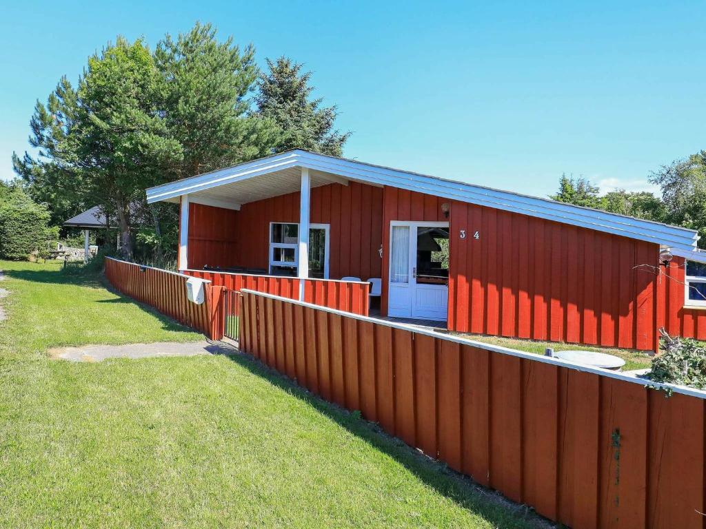 una casa roja con una valla delante en 6 person holiday home in Bindslev, en Bindslev