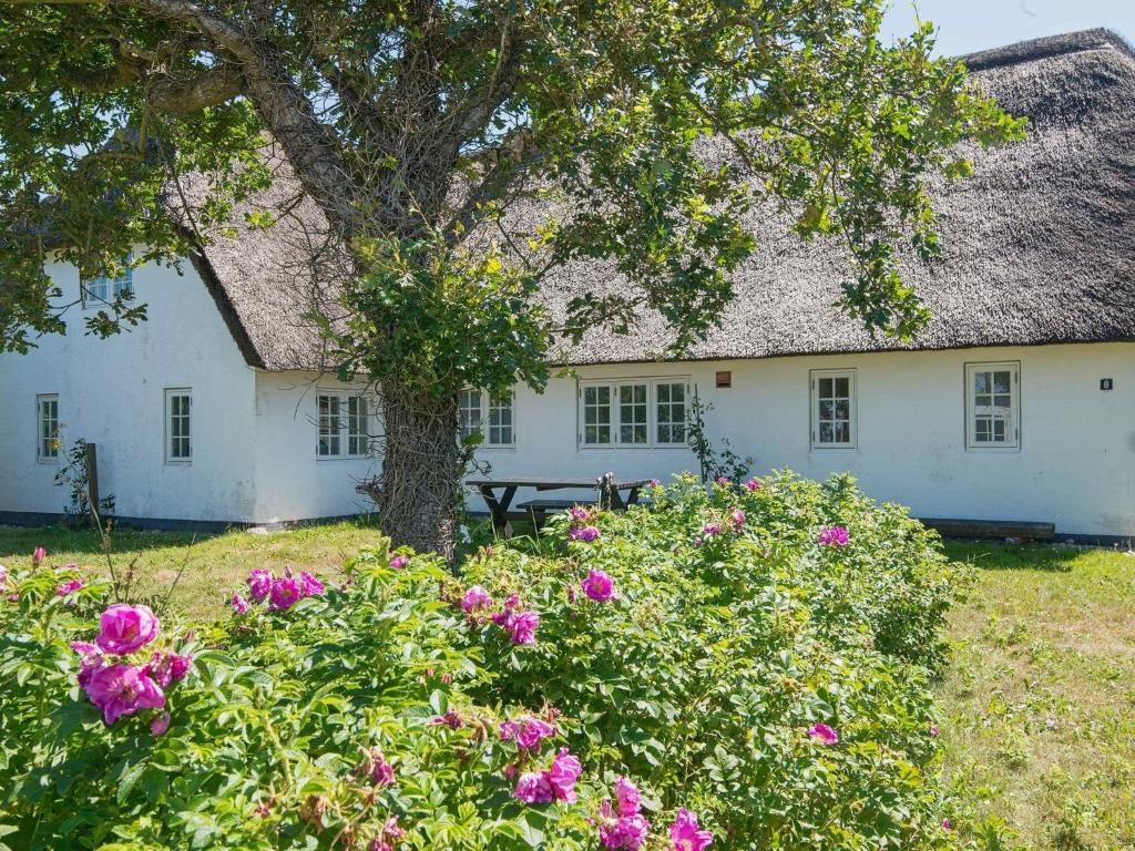 ein weißes Haus mit einem Baum und rosa Blumen in der Unterkunft Holiday home Bredebro in Ballum
