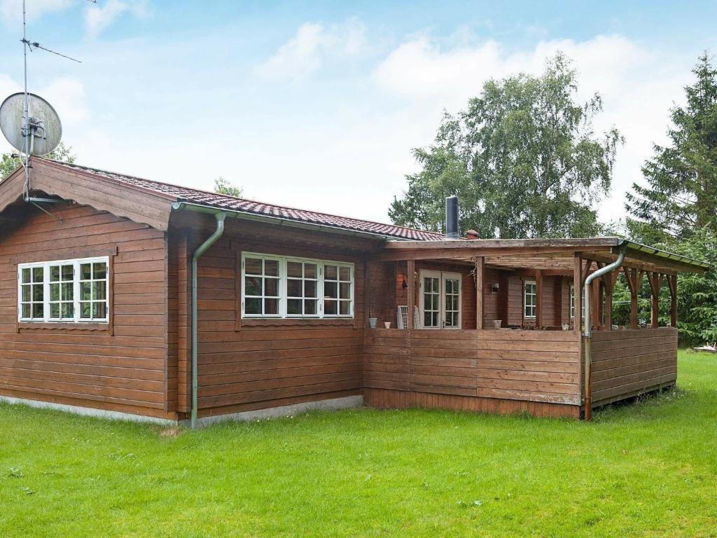 6 person holiday home in F rvang في Fårvang: منزل خشبي صغير على ميدان عشبي