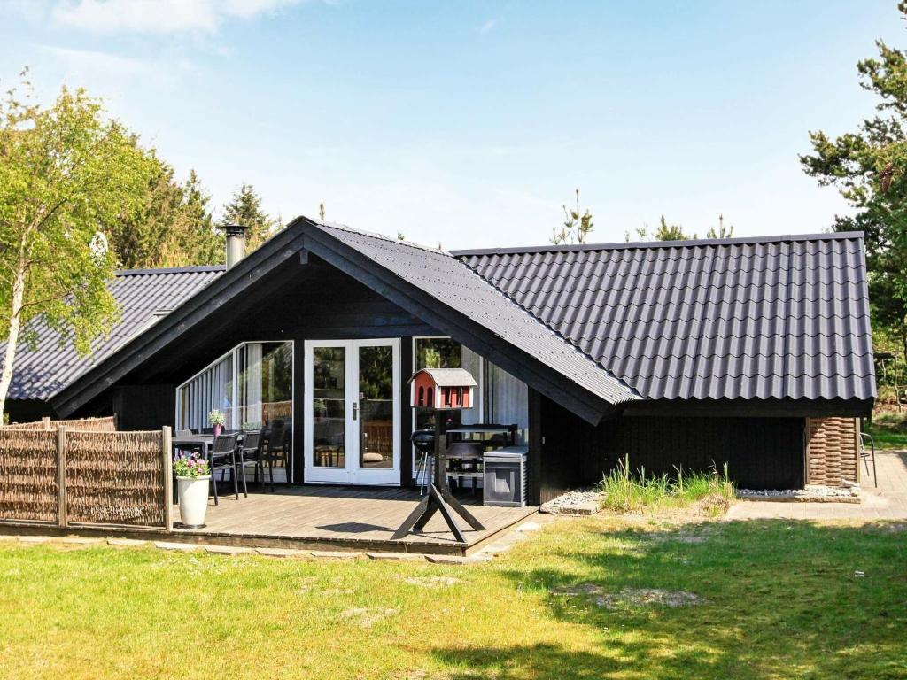 una casa con techo negro y patio en 6 person holiday home in Saltum en Saltum