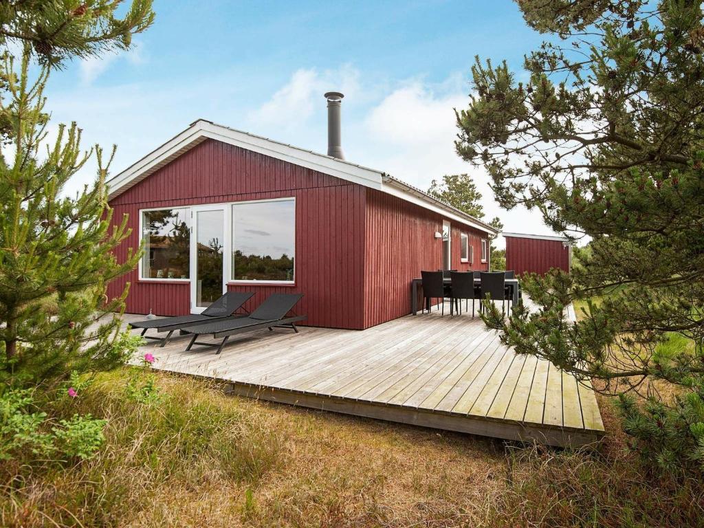 een rood gebouw met stoelen op een houten terras bij Three-Bedroom Holiday home in Rømø 35 in Bolilmark