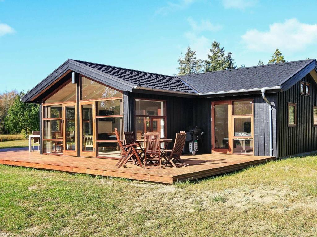 a small black house with a deck and chairs at Holiday Home Kandestedvej in Starholm