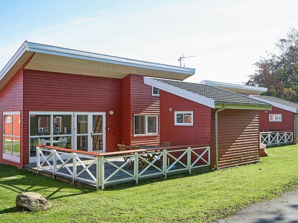 een rode hut met een veranda en een tuin bij 6 person holiday home in Gudhjem in Gudhjem