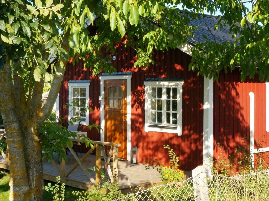 una casa roja con un porche y un árbol en Holiday Home Målaretorpsvägen, en Borgholm
