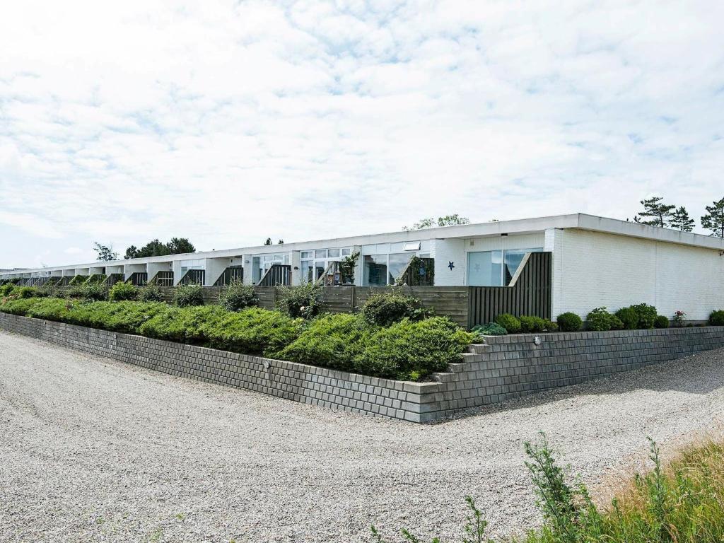 un largo edificio blanco con una pared de retención de ladrillos en 4 person holiday home in R m, en Rømø Kirkeby