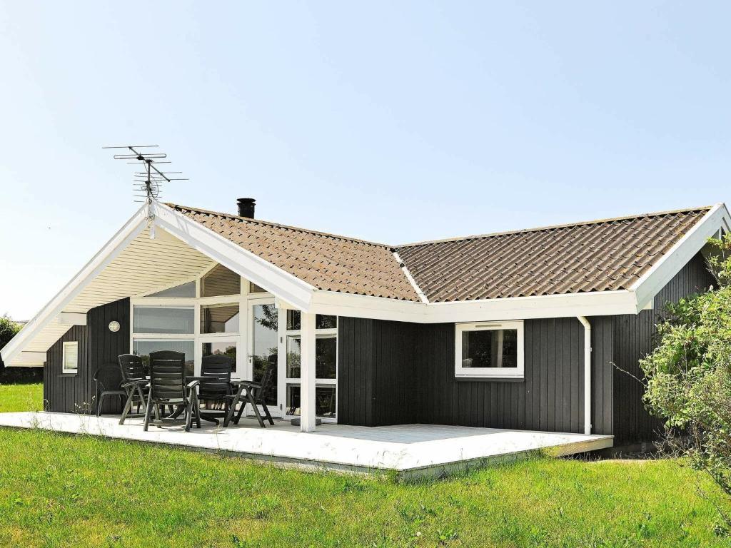 ein kleines schwarzes Haus mit einer Terrasse und Stühlen in der Unterkunft 6 person holiday home in Ebberup in Helnæs By