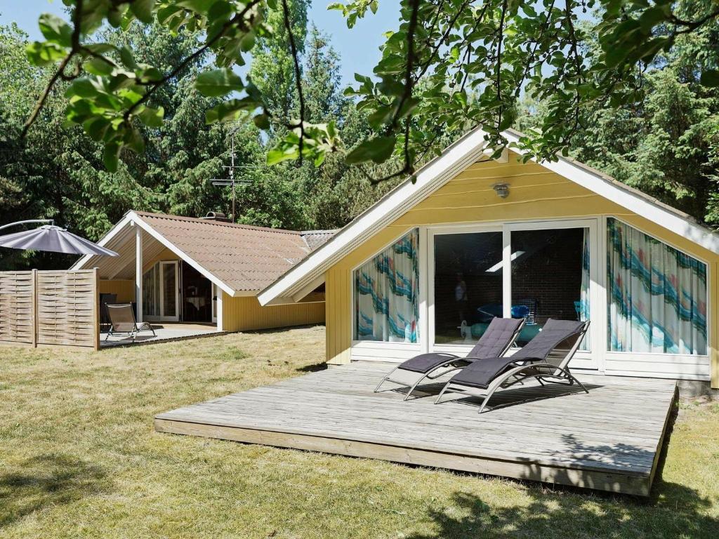 two lounge chairs on a deck in front of a house at 8 person holiday home in Aakirkeby in Vester Sømarken