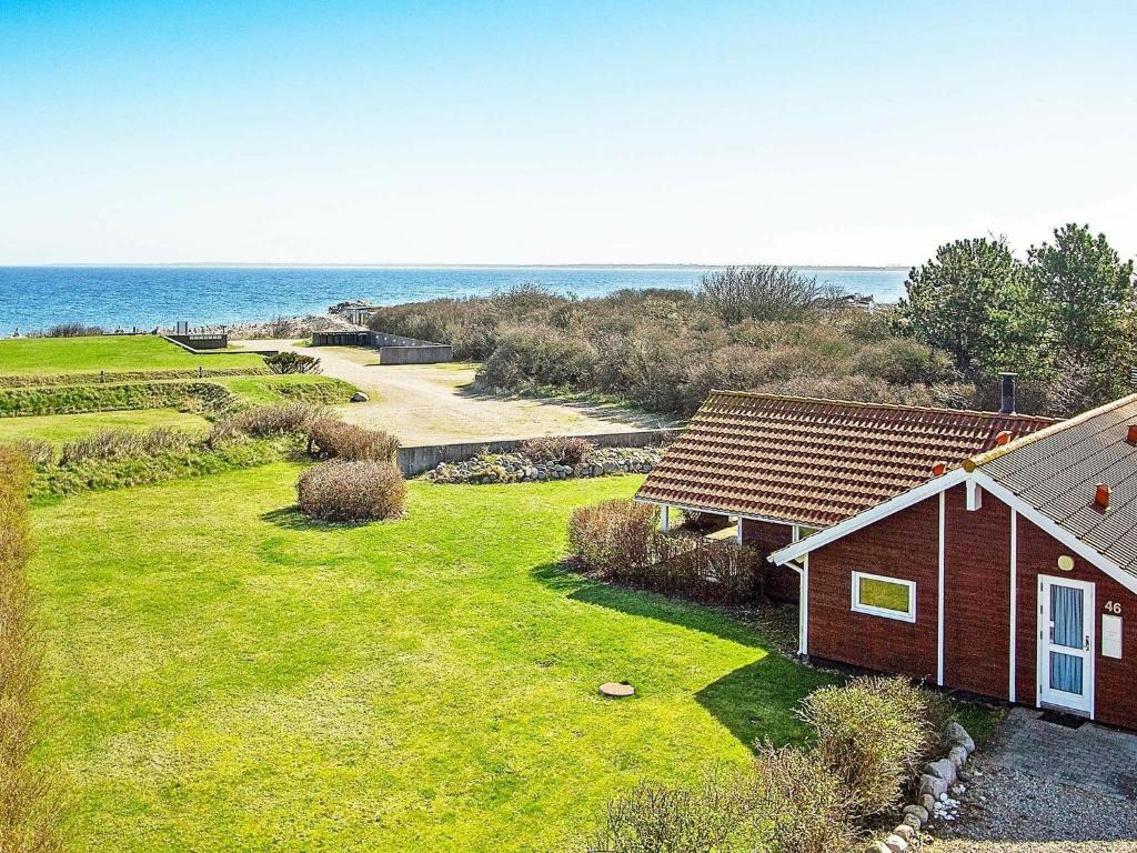 a house on a grass field next to the ocean at Three-Bedroom Holiday home in Nykøbing Sj 7 in Lumsås