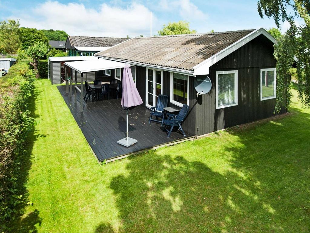 a small house with a deck with chairs on it at Three-Bedroom Holiday home in Juelsminde 15 in Sønderby