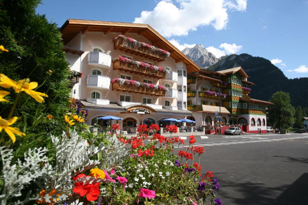 ein großes Gebäude mit Blumen davor in der Unterkunft Hotel Alba Wellness & Spa in Canazei