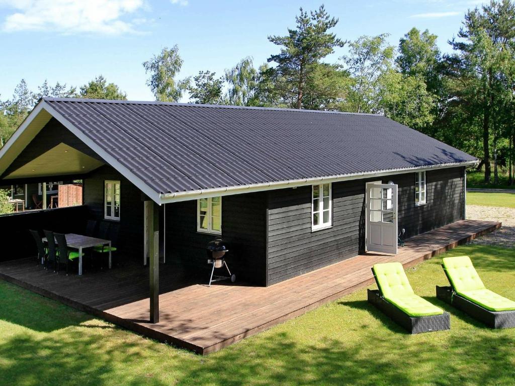 a small black house with a wooden deck at Holiday Home Den II in Læsø
