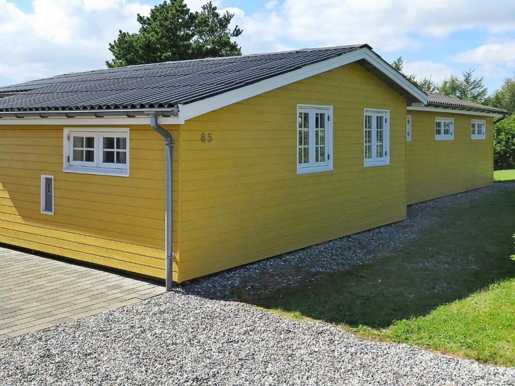 ein gelbes Gebäude mit weißen Fenstern und einer Auffahrt in der Unterkunft Two-Bedroom Holiday home in Struer 4 in Oddesund Syd