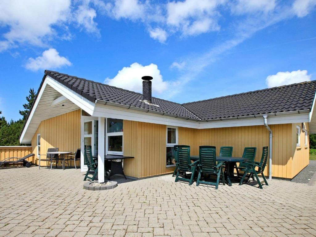 ein Haus mit einer Terrasse mit Stühlen und einem Tisch in der Unterkunft 8 person holiday home in Bl vand in Blåvand
