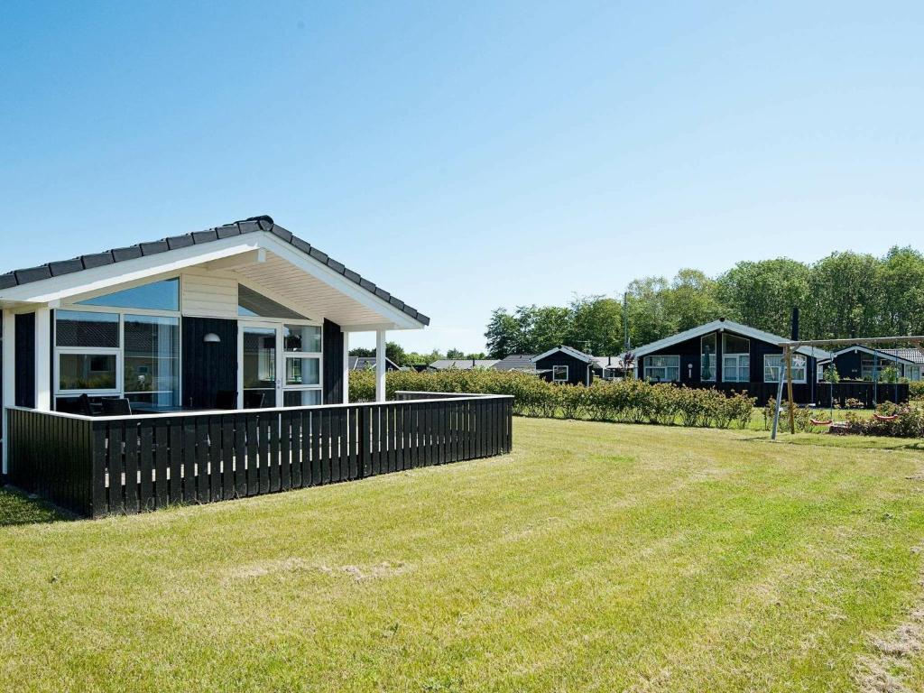 a house with a fence in front of a yard at Three-Bedroom Holiday home in Juelsminde 18 in Sønderby