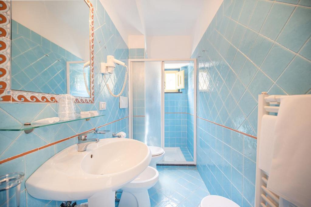 a blue tiled bathroom with a sink and a toilet at Solcalante in Procida
