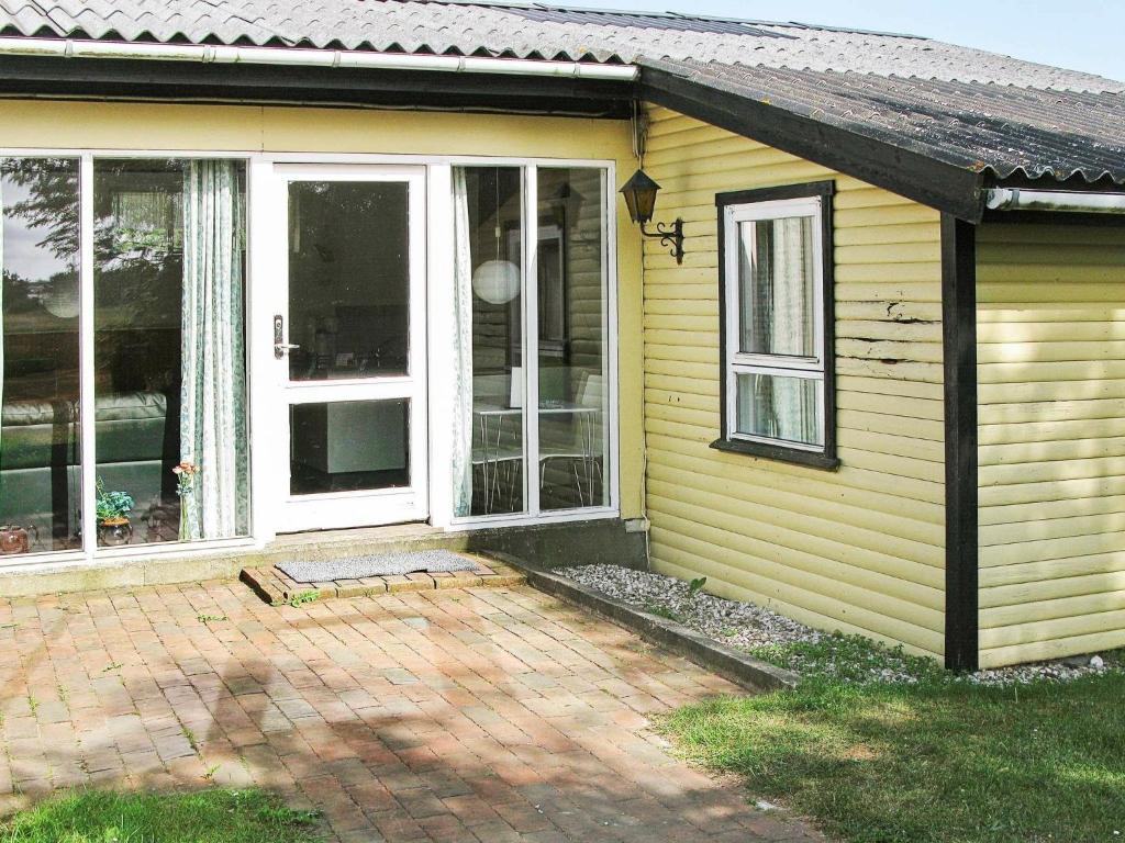 Nørre Vorupørにある4 person holiday home in Thistedのパティオとガラスの引き戸が付いた黄色の家