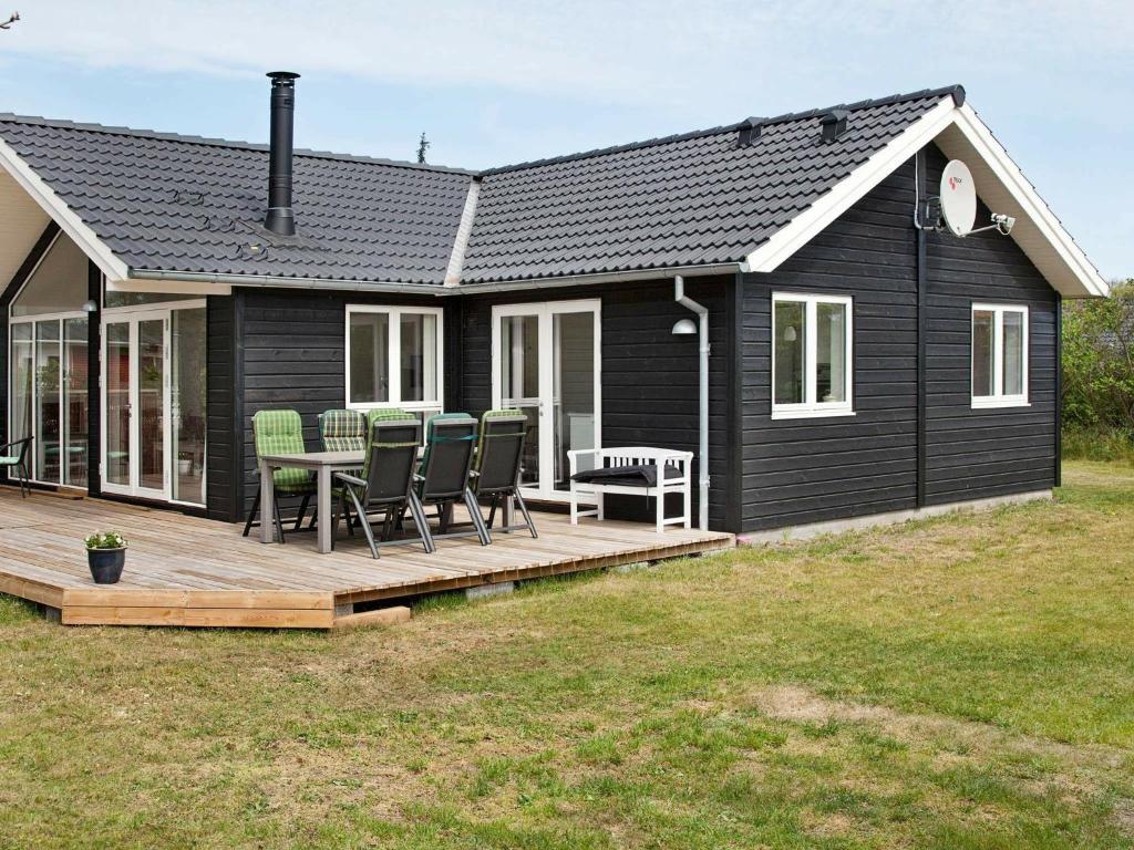 Stillinge Strandにある6 person holiday home in Slagelseの黒い家(椅子とテーブル付きのデッキ付)