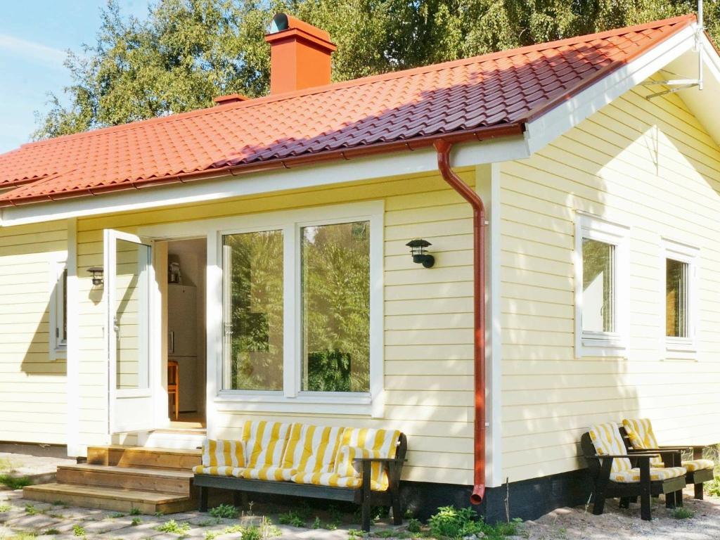 una pequeña casa blanca con un banco delante en 3 person holiday home in FJ LKINGE en Fjälkinge