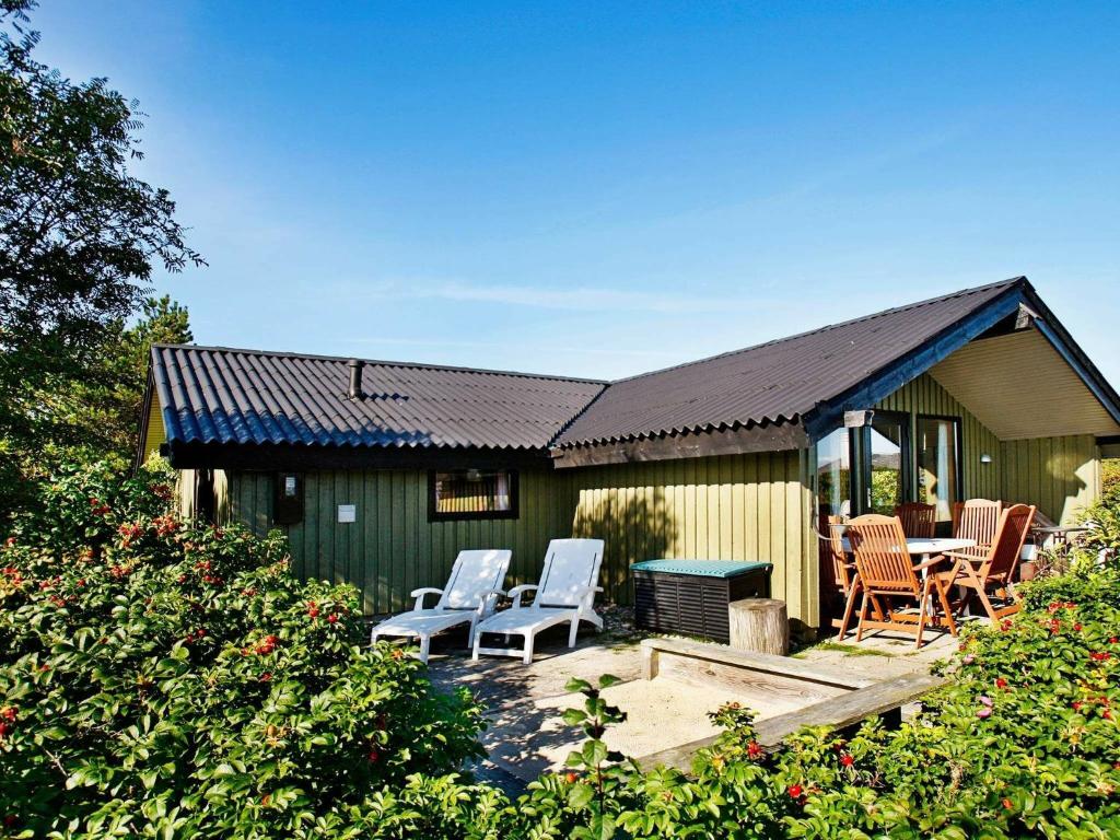 ein grünes Haus mit Stühlen und einer Terrasse in der Unterkunft Three-Bedroom Holiday home in Lemvig 8 in Lemvig