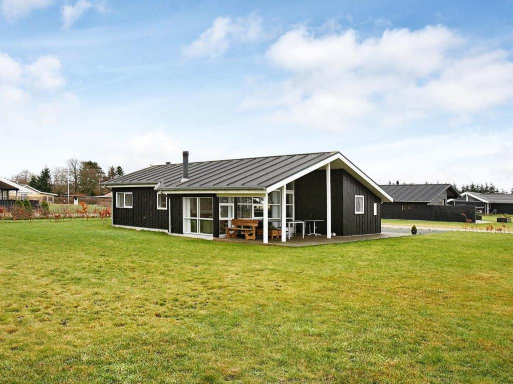 6 person holiday home in Hadsund في Øster Hurup: منزل أسود مع ميدان عشبي كبير