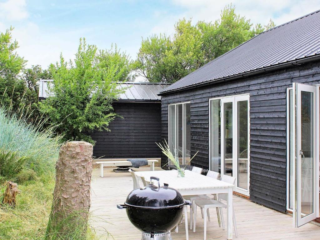 una griglia su una terrazza di legno accanto a una casa di 9 person holiday home in Hj rring a Lønstrup