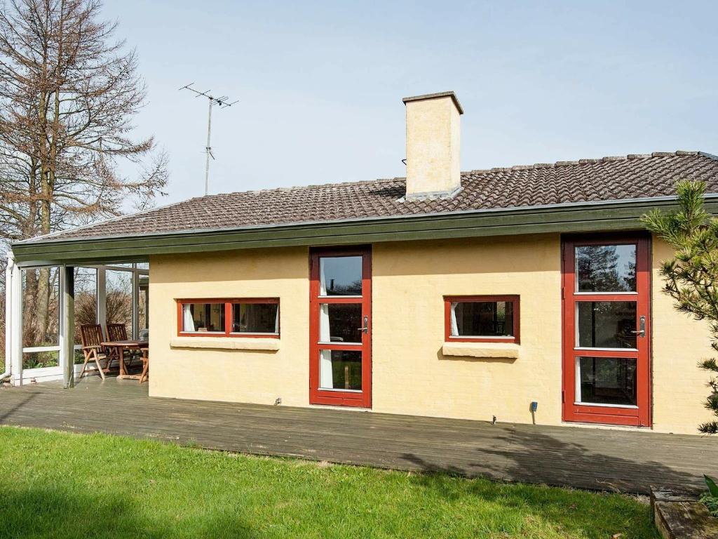 een geel huis met rode ramen en een terras bij Holiday home Børkop III in Børkop