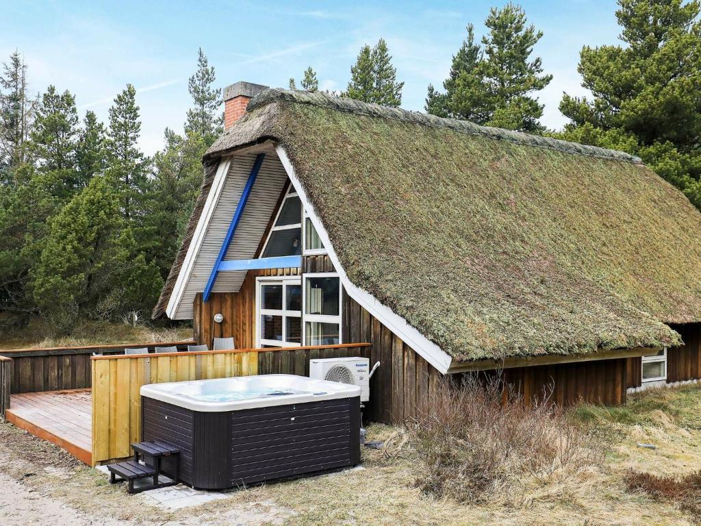 una casa con tetto di paglia e vasca idromassaggio di Four-Bedroom Holiday home in Blåvand 39 a Blåvand