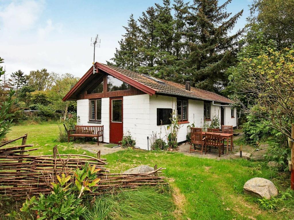 una pequeña casa blanca con una mesa de picnic en un patio en 6 person holiday home in Nyk bing Sj, en Nyrup