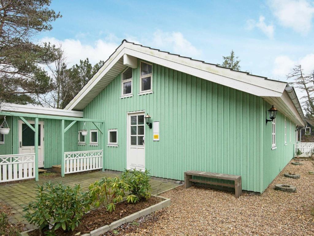 una casa verde con un banco delante en 8 person holiday home in Hemmet en Hemmet