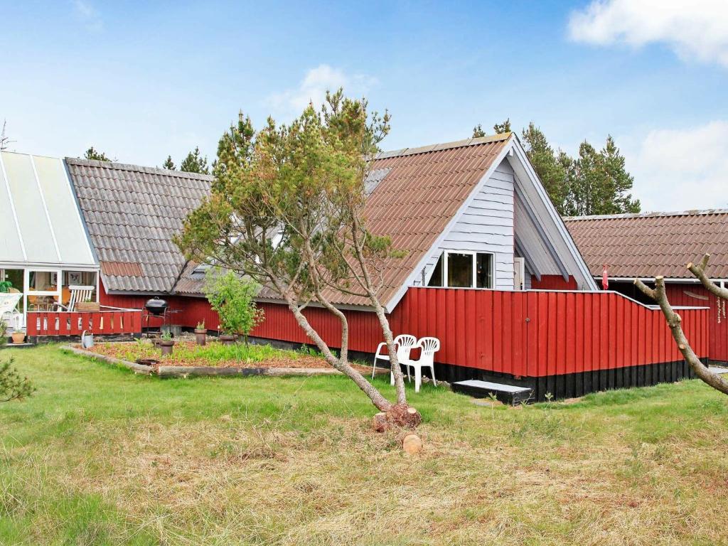 ブラーバンドにあるThree-Bedroom Holiday home in Blåvand 69の庭木のある赤白家屋