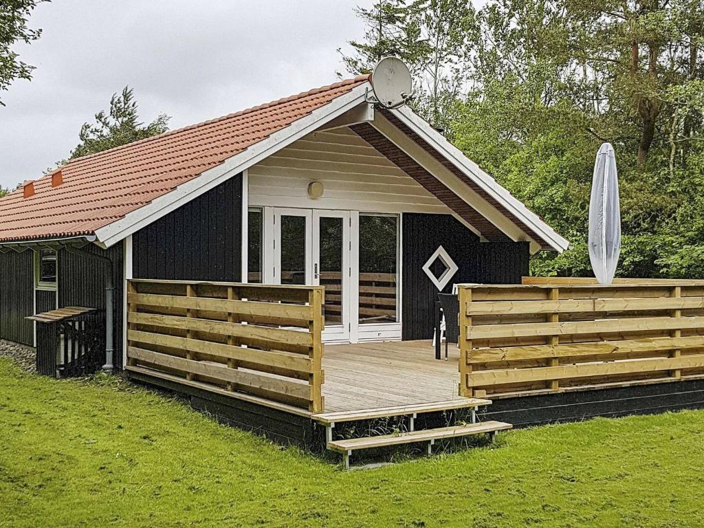 ein kleines Haus mit einer Terrasse und einem Sonnenschirm in der Unterkunft 6 person holiday home in Oksb l in Oksbøl