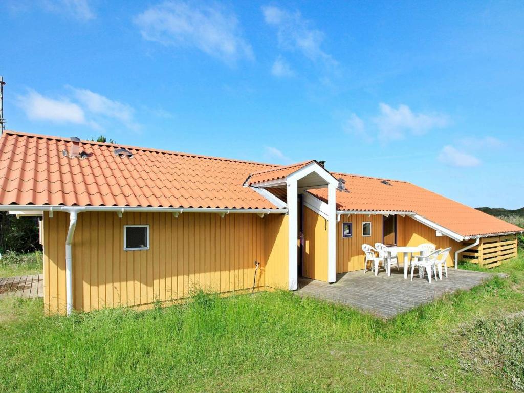 a yellow house with a table and chairs on a deck at 8 person holiday home in Oksb l in Vejers Strand