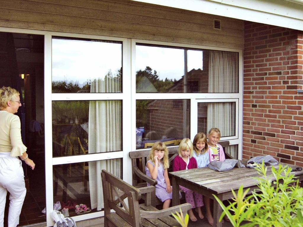 un grupo de niños sentados alrededor de una mesa de madera en un patio en 5 person holiday home in Bl vand en Blåvand