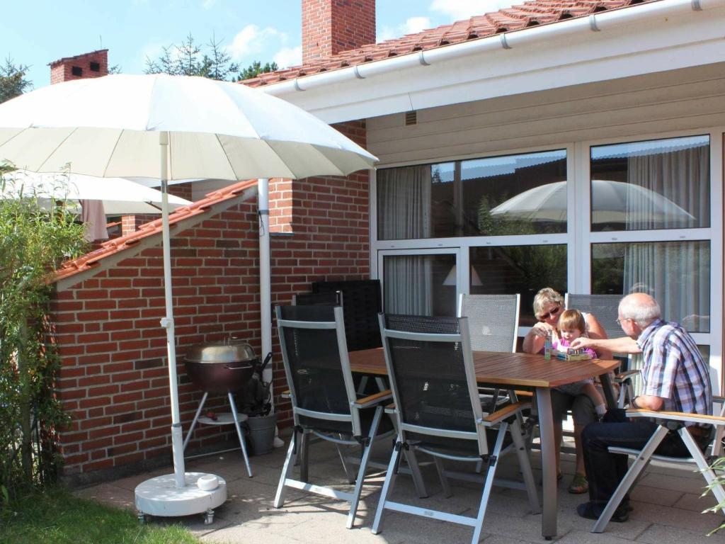 Holiday Home Fyrvej VI في بلافاند: يجلس رجل وطفل على طاولة مع مظلة
