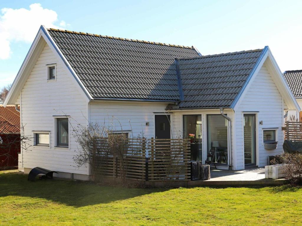 een klein wit huis met een zwart dak bij 4 person holiday home in FALKENBERG in Falkenberg