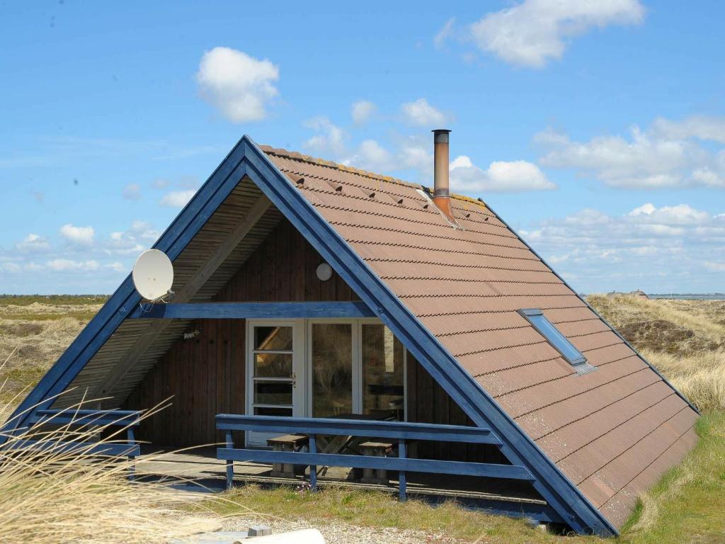 una pequeña casa con un techo inclinado en un campo en 6 person holiday home in Ringk bing, en Klegod