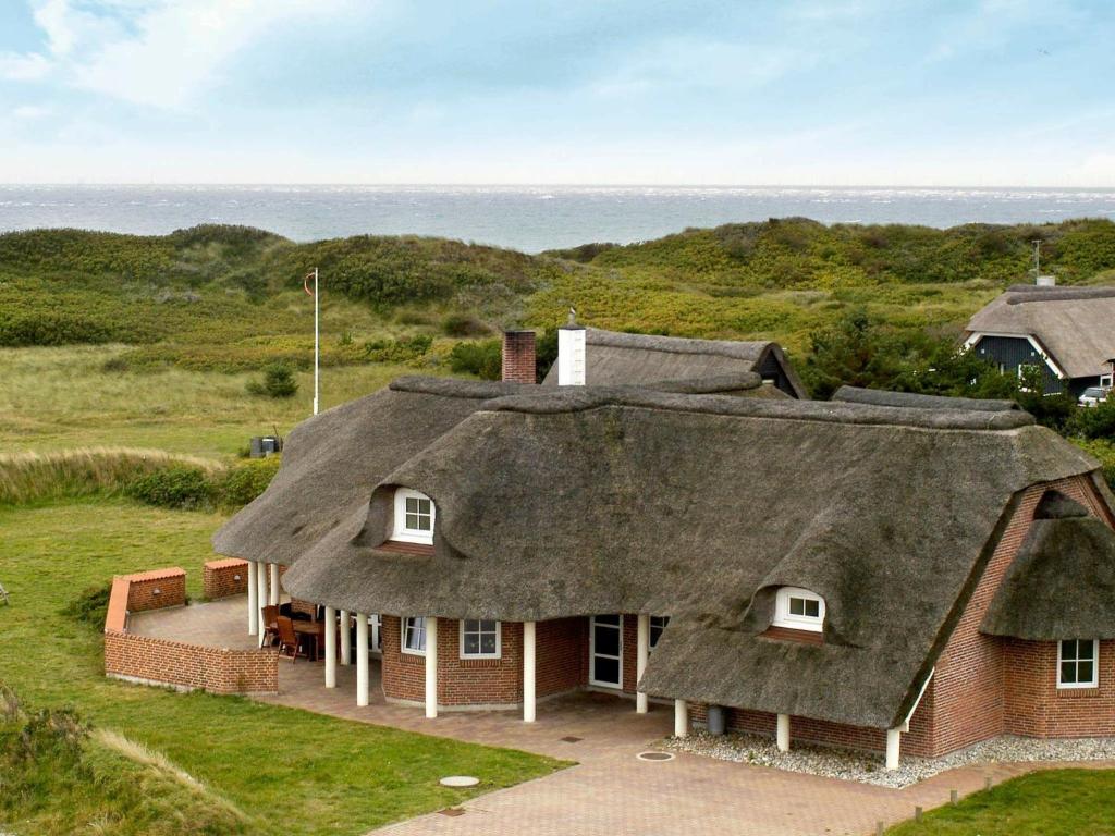 dom z dachem krytym strzechą i widokiem na ocean w obiekcie 10 person holiday home in Bl vand w mieście Blåvand