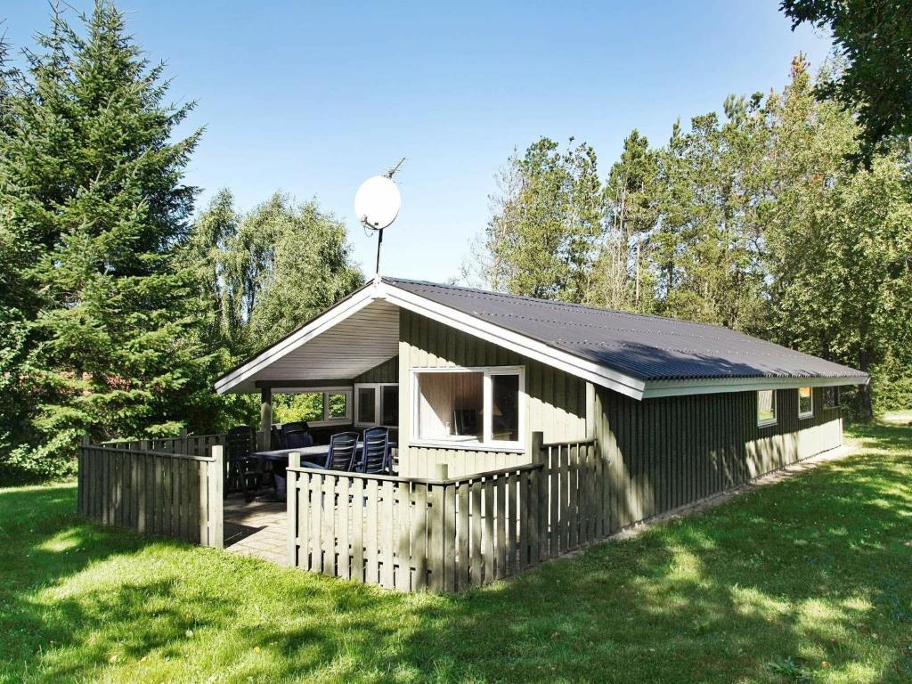um pequeno barracão com uma cerca num quintal em 6 person holiday home in Fjerritslev em Fjerritslev