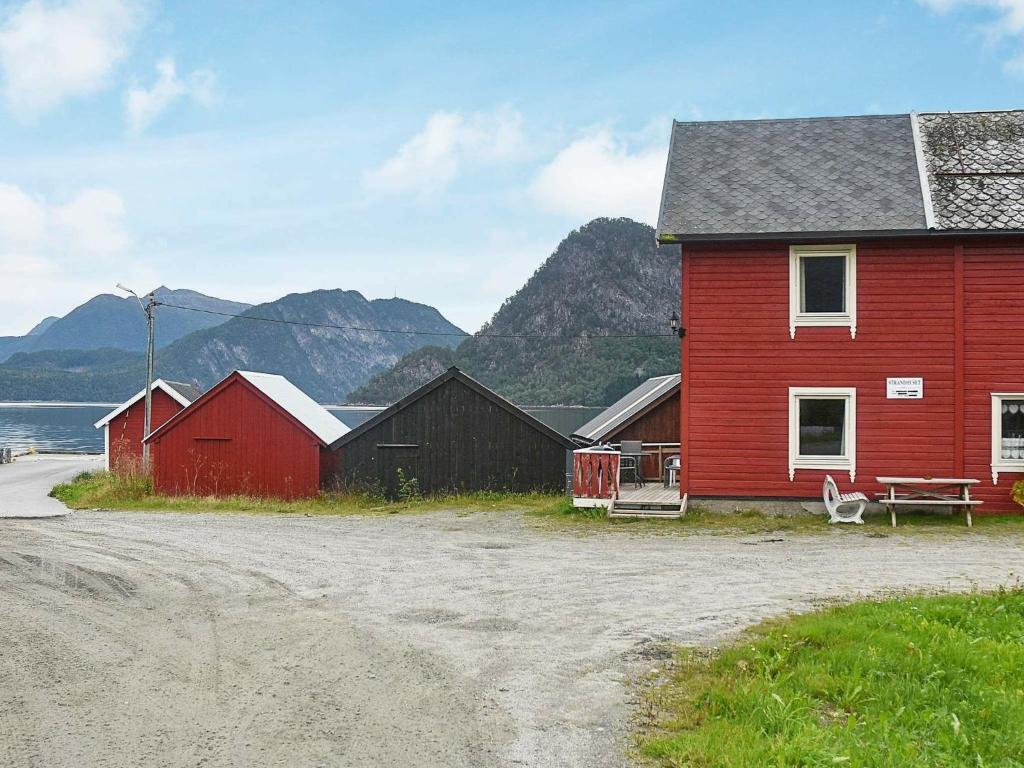a red house and two buildings with mountains in the background at Holiday home Måndalen in Sæbø