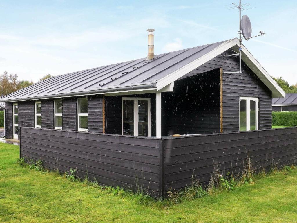 una casa negra con techo de gambrel en 6 person holiday home in Hals en Hals