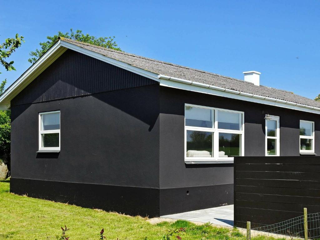 une maison noire avec des fenêtres blanches sur son côté dans l'établissement Four-Bedroom Holiday home in Frørup, à Tårup