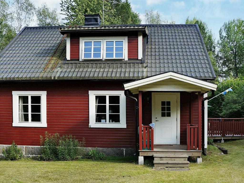 ein rotes Haus mit einer weißen Tür und Fenstern in der Unterkunft Three-Bedroom Holiday home in Hallabro in Hallabro