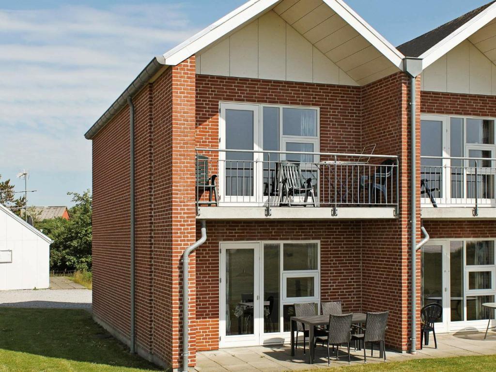 a brick house with a balcony and a table and chairs at 6 person holiday home in H jer in Emmerlev