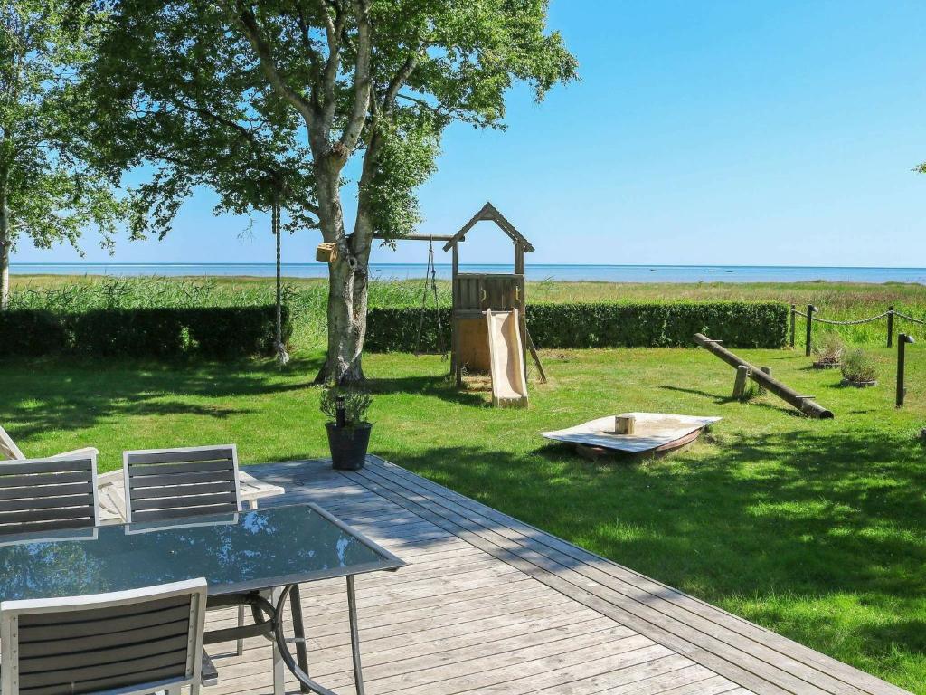 Helberskovにある5 person holiday home in Hadsundの木とブランコのあるデッキ(テーブルと椅子付)