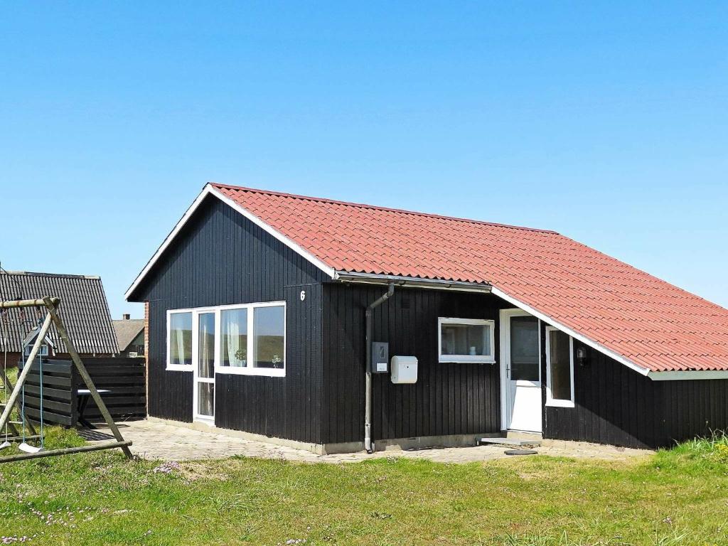 a black house with a red roof at 8 person holiday home in Harbo re in Vrist
